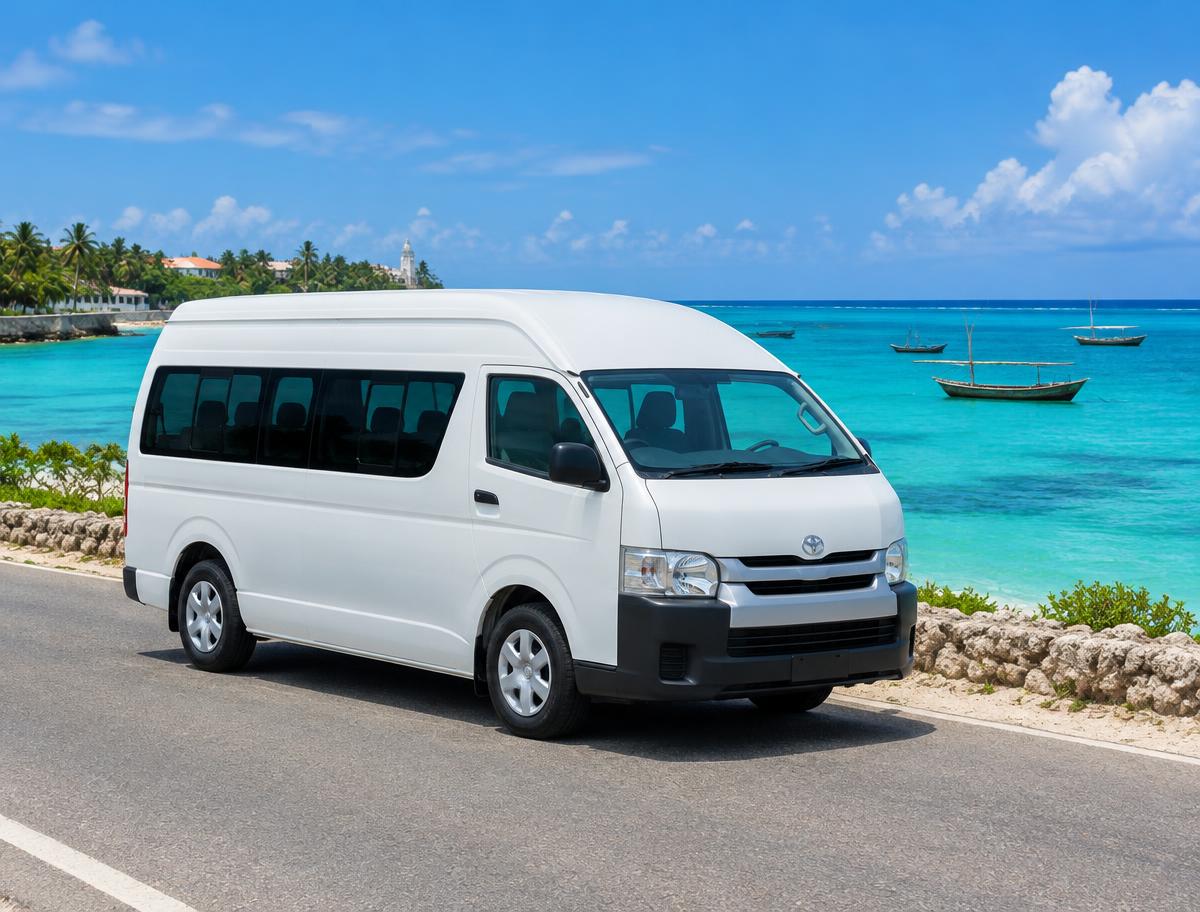 White Toyota Hiace minibus on a coastal road with turquoise sea behind